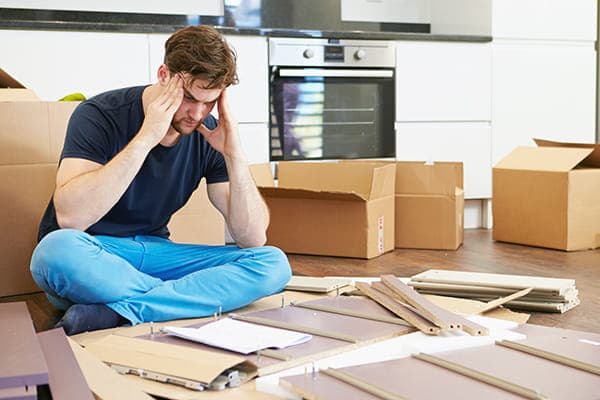 Frustrated person surrounded by flat-pack furniture pieces